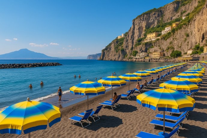 Spiaggia di Alimuri a Meta di Sorrento, ombrelloni giallo-blu aperti e mare calmo.