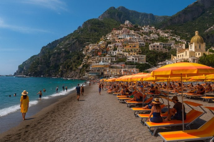 Spiaggia di Marina Grande a Positano con ombrelloni giallo-arancio e case sulla scogliera.