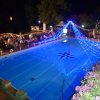 Piscina illuminata con decorazioni e luci blu di notte.