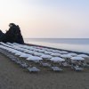 Spiaggia con file ordinate di lettini e ombrelloni bianchi al tramonto.