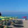 Spiaggia con file di ombrelloni giallo-verdi e mare calmo.