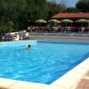 Piscina con un nuotatore e file di lettini blu, ombrelloni e fiori di sfondo.