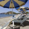 Spiaggia con ombrelloni blu e gialli, lettini e mare calmo.