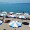 Ombrelloni bianchi e blu su una spiaggia di sabbia davanti al mare.