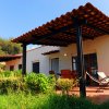 Bungalow con tetto a tegole, sedie in legno e sdraio su un patio circondato da vegetazione.