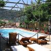 Piscina circondata da alberi e lettini, struttura in legno sopraelevata.