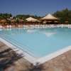 Grande piscina all'aperto con lettini e ombrelloni arancioni.