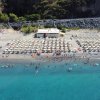 Spiaggia affollata con ombrelloni e mare blu.